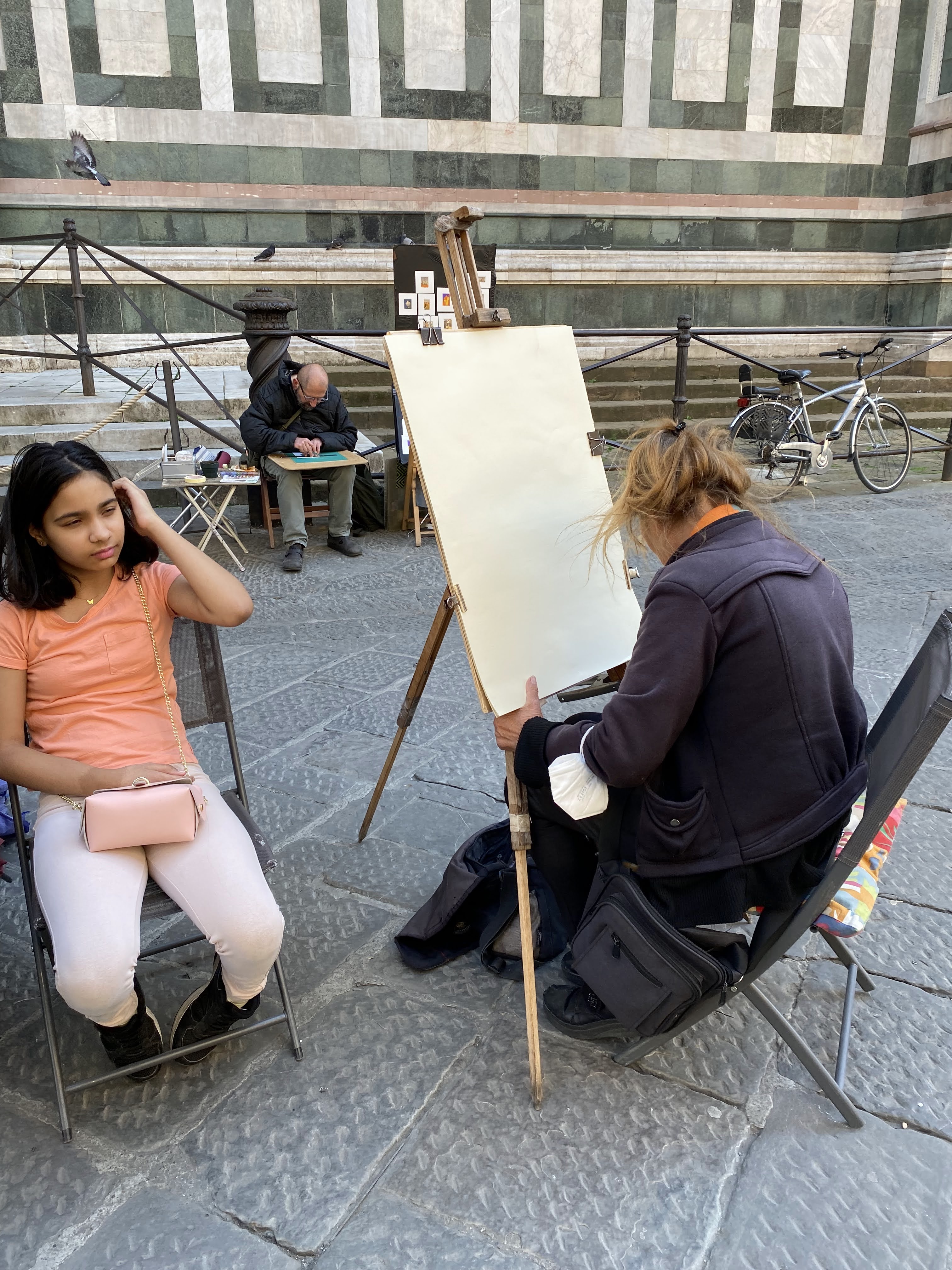 My daughter patiently posing for a street artist drawing her portrait.