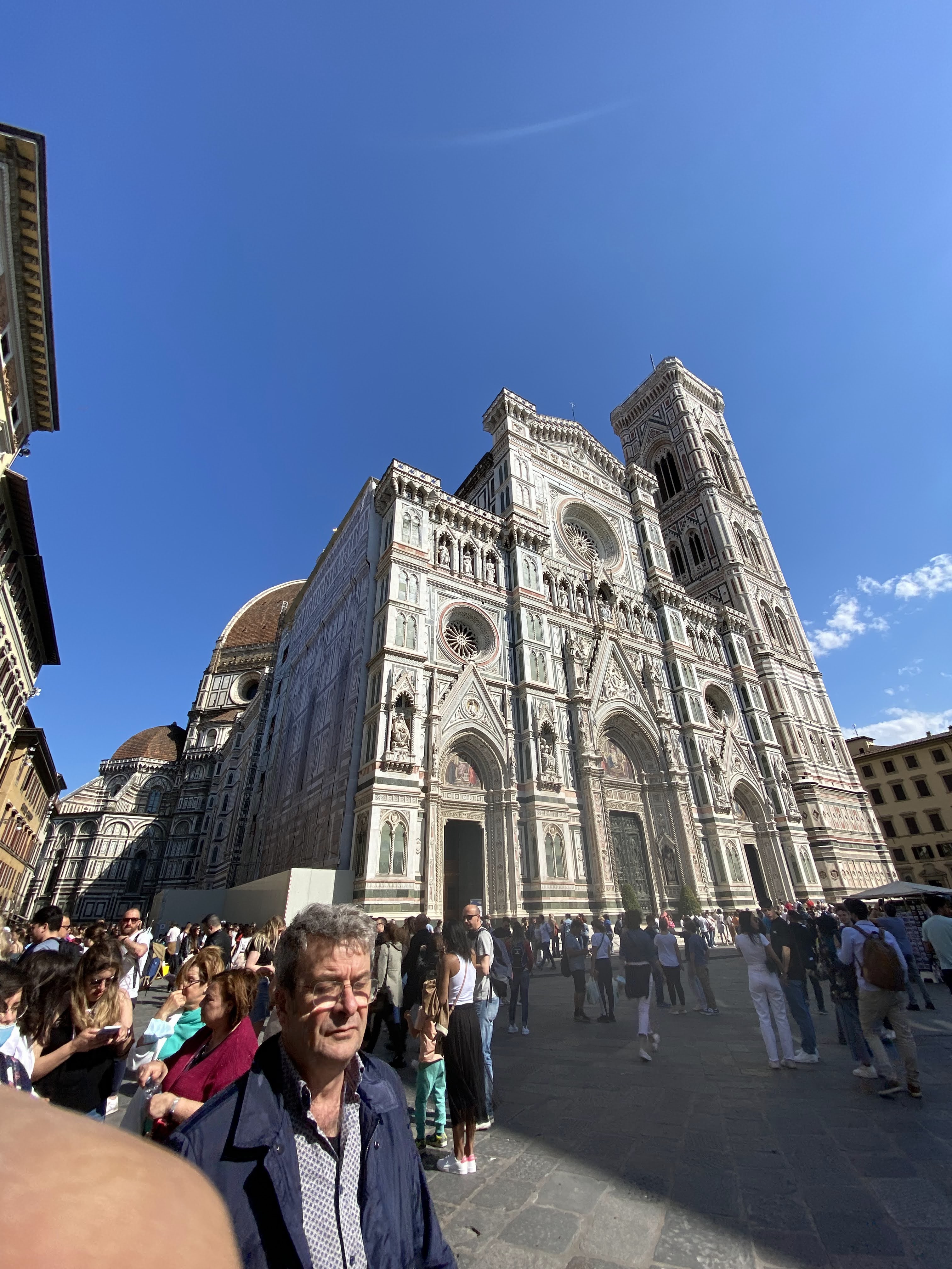 The magnificent Florence Duomo under a clear blue sky, bustling with people.