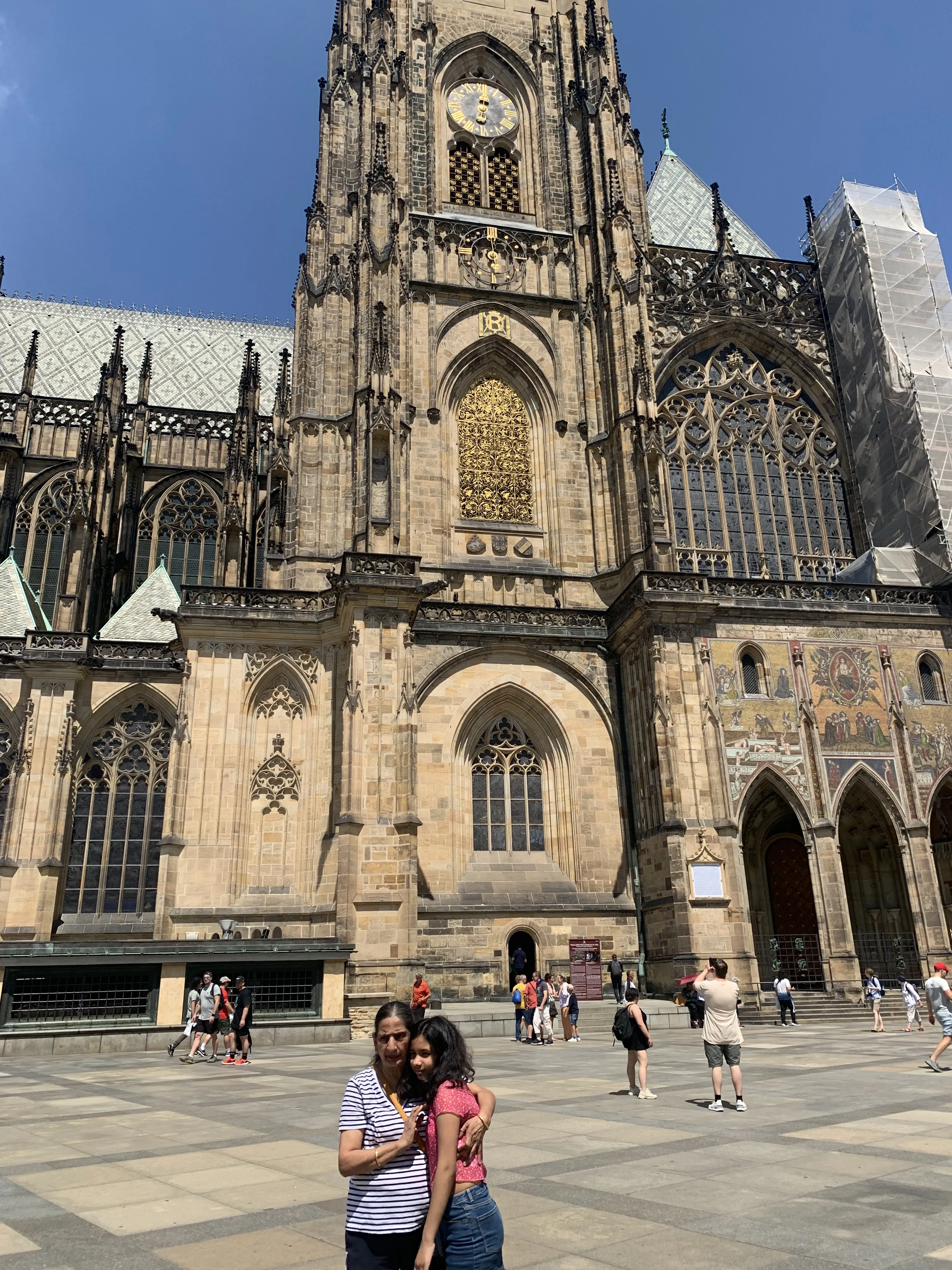 My mother and daughter smiling in front of the grand St. Vitus Cathedral in Prague.