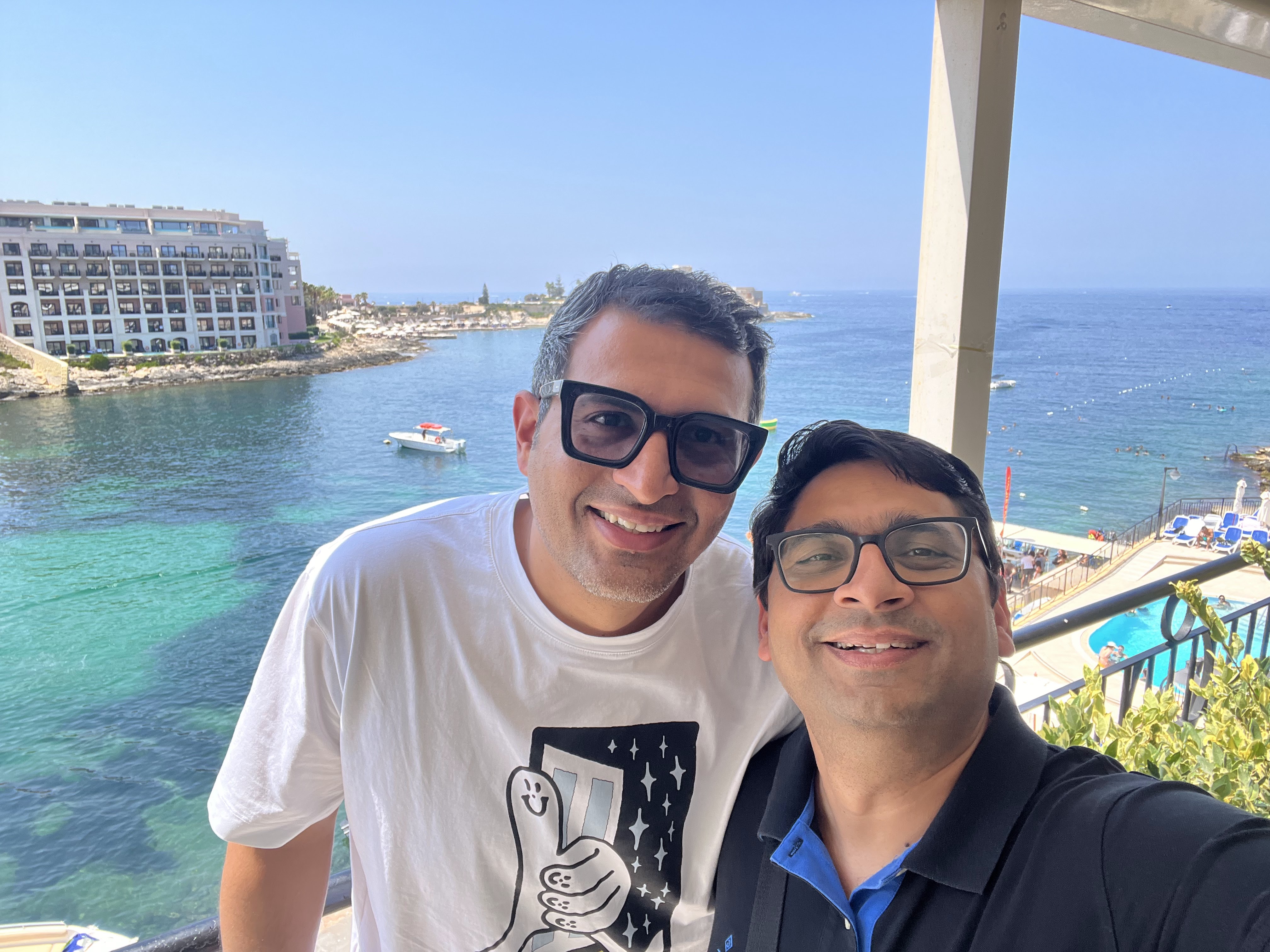 A smiling selfie of two friends against the backdrop of a beautiful Maltese bay